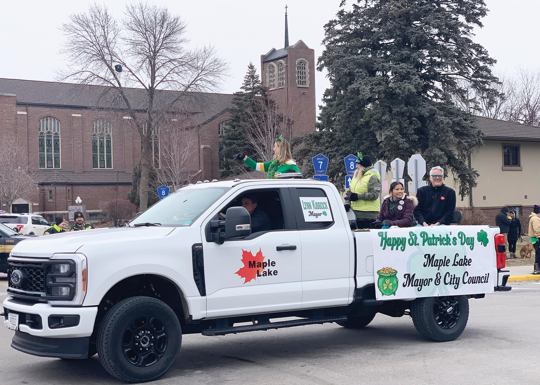Maple Lake Mayor Lynn Kissok waves to parade goers, while members of the city council smile at the crowd.