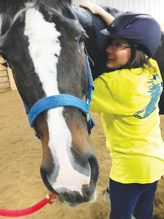Relationships between rider and horse are a big part of the therapy program at Freedom Farm. Above, Cassie gets lots of love from her rider, Sarah.