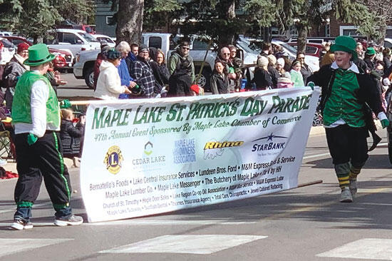 On a windy day, banner bearers had to work hard to keep the Maple Lake St. Patrick’s Day Parade sign from blowing in the stiff breeze.