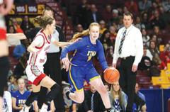 STMA’s Mackenzie Kramer (right) dribbles by a defender in a 67-58 state quarterfinal victory over Lakeville North. In the background is Head Coach Kent Hamre. (Photo by Rob LaPlante)